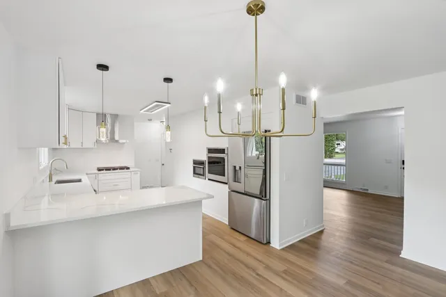 a large kitchen with white cabinets stainless steel appliances