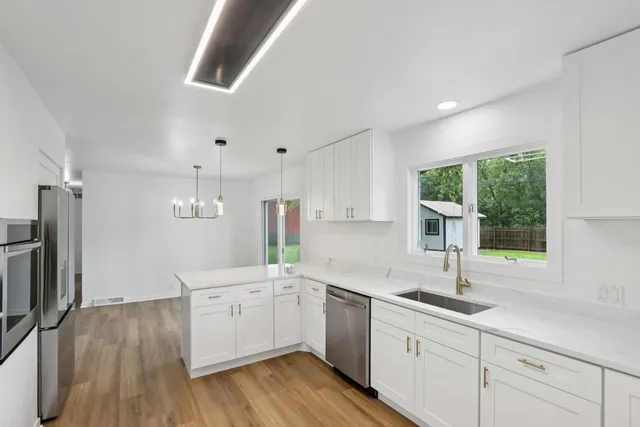 a kitchen with cabinets stainless steel appliances and wooden floor