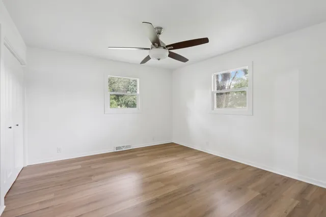 an empty room with wooden floor and ceiling fan