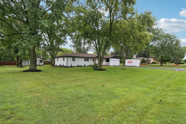 a view of a house with a big yard and large trees