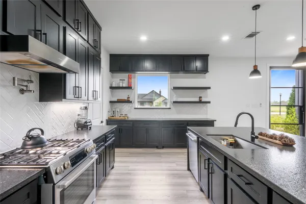 a kitchen with stainless steel appliances granite countertop a sink stove and refrigerator