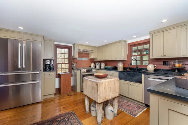 a kitchen with a refrigerator a stove a sink dishwasher and a dining table with wooden floor