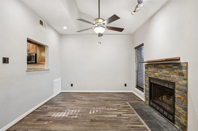 a view of a livingroom with a fireplace a ceiling fan and chandelier
