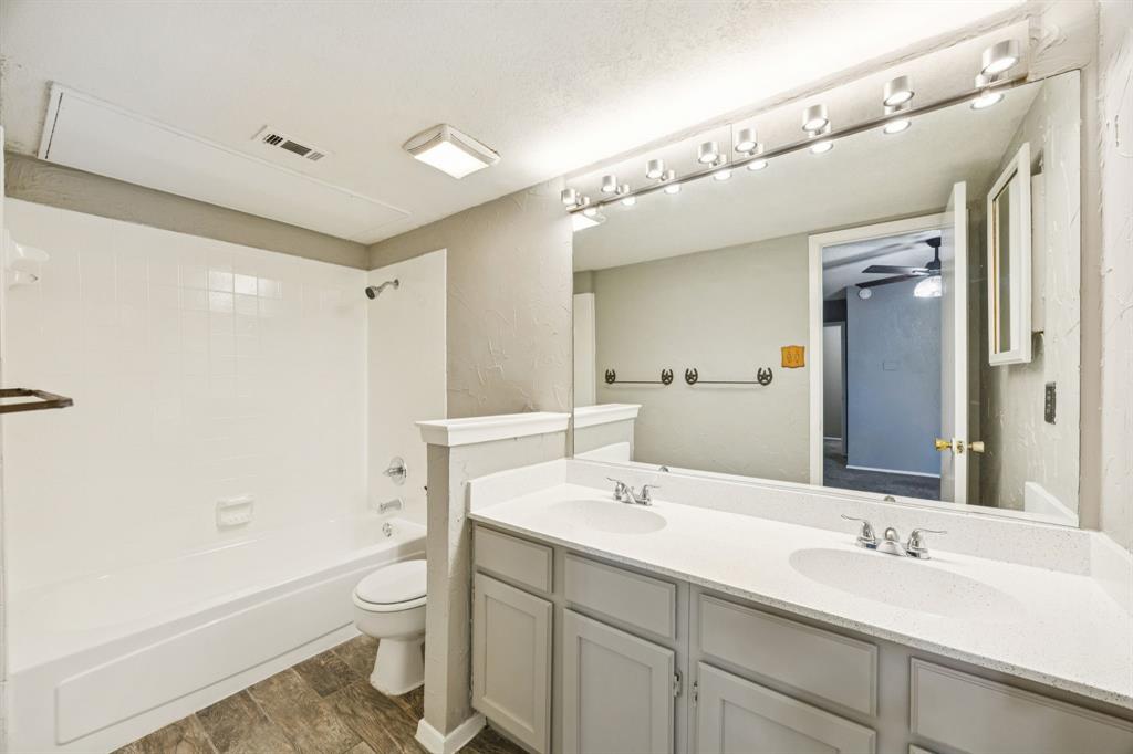 6814 Dolphin Circle Rowlett, TX 75088 - Photo 9 of 30 a bathroom with a sink a toilet a large mirror and shower