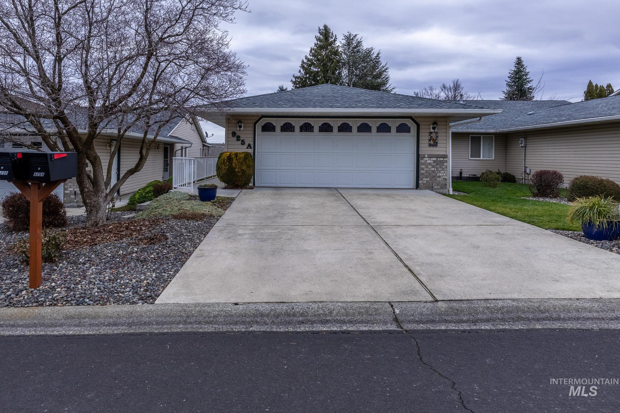 Ranch-style house featuring concrete driveway, roof with shingles, and a garage