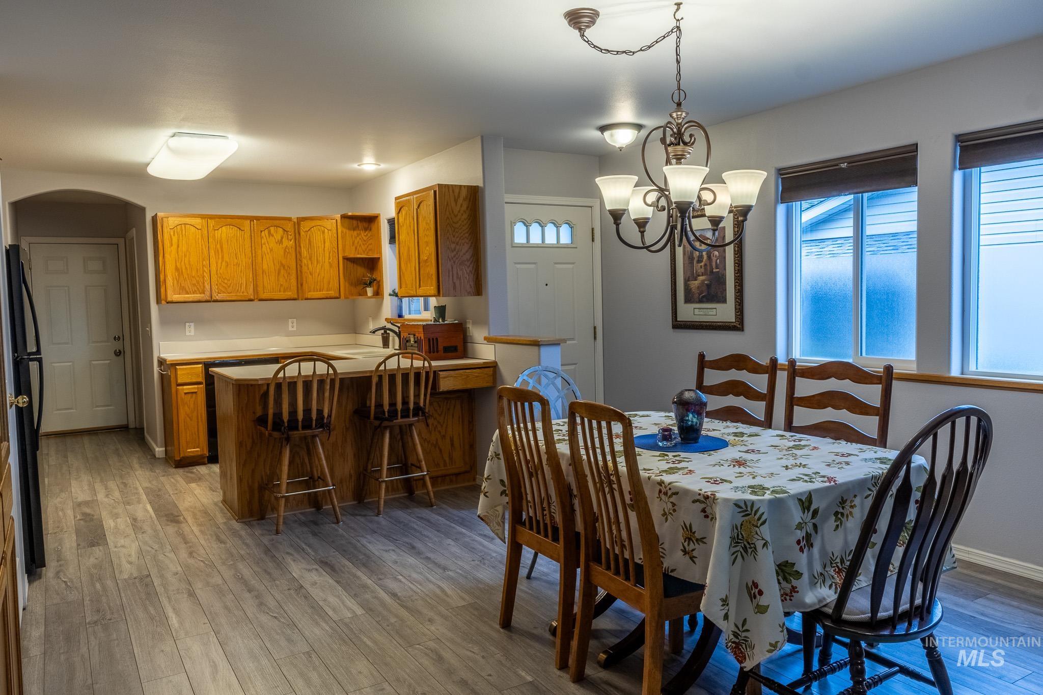 925 Hawthorne Street, Unit A Lewiston, ID 83501 - Photo 5 of 25 Dining space featuring arched walkways, a chandelier, and light wood-style flooring
