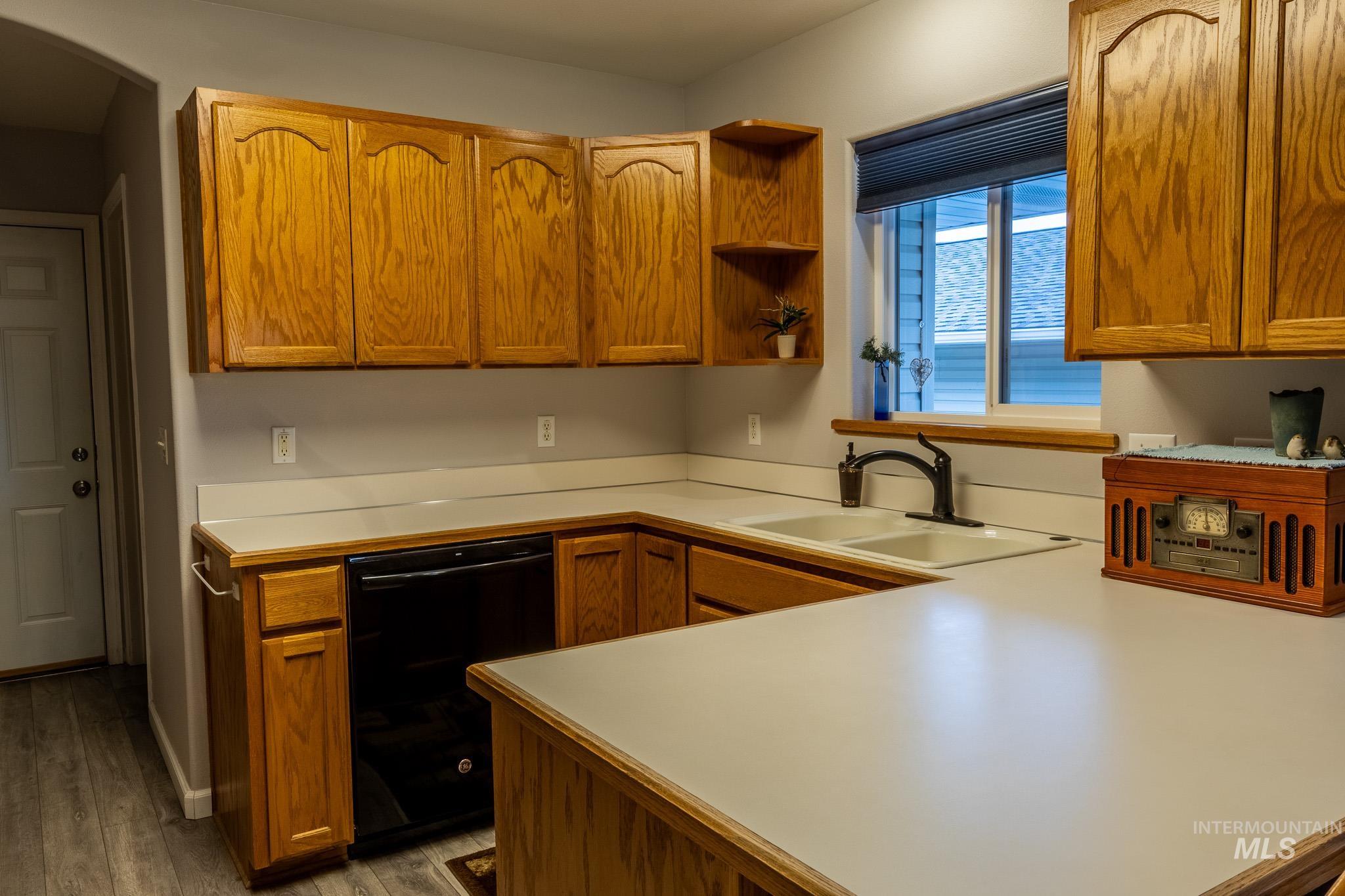 925 Hawthorne Street, Unit A Lewiston, ID 83501 - Photo 6 of 25 Kitchen featuring light countertops, brown cabinetry, black dishwasher, open shelves, and dark wood-style floors