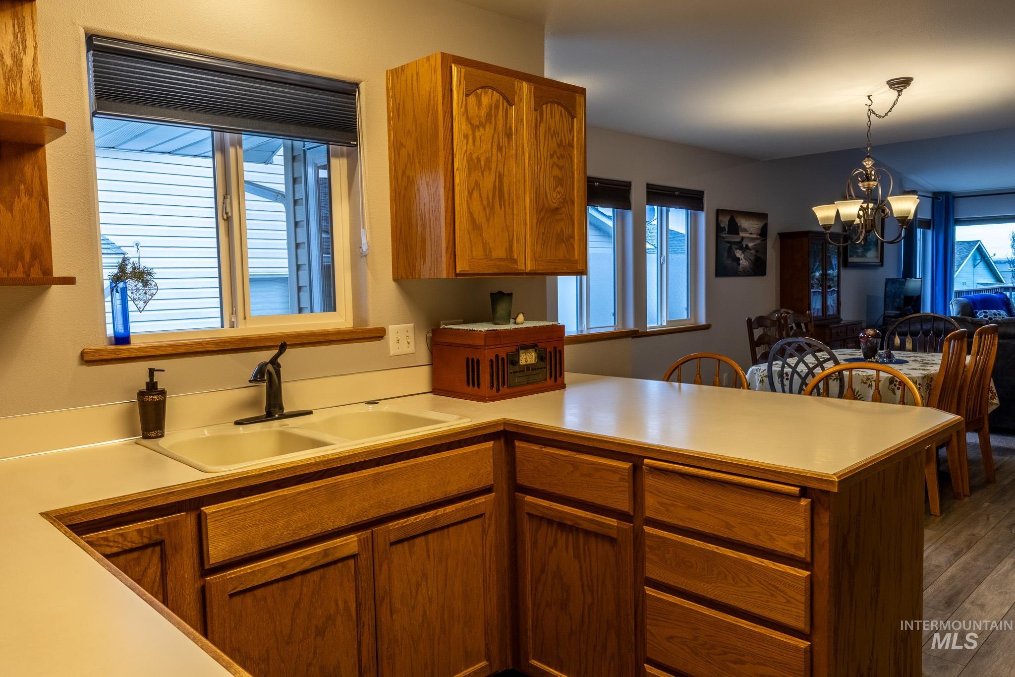 925 Hawthorne Street, Unit A Lewiston, ID 83501 - Photo 7 of 25 Kitchen featuring light countertops, a peninsula, a chandelier, brown cabinetry, and hanging light fixtures