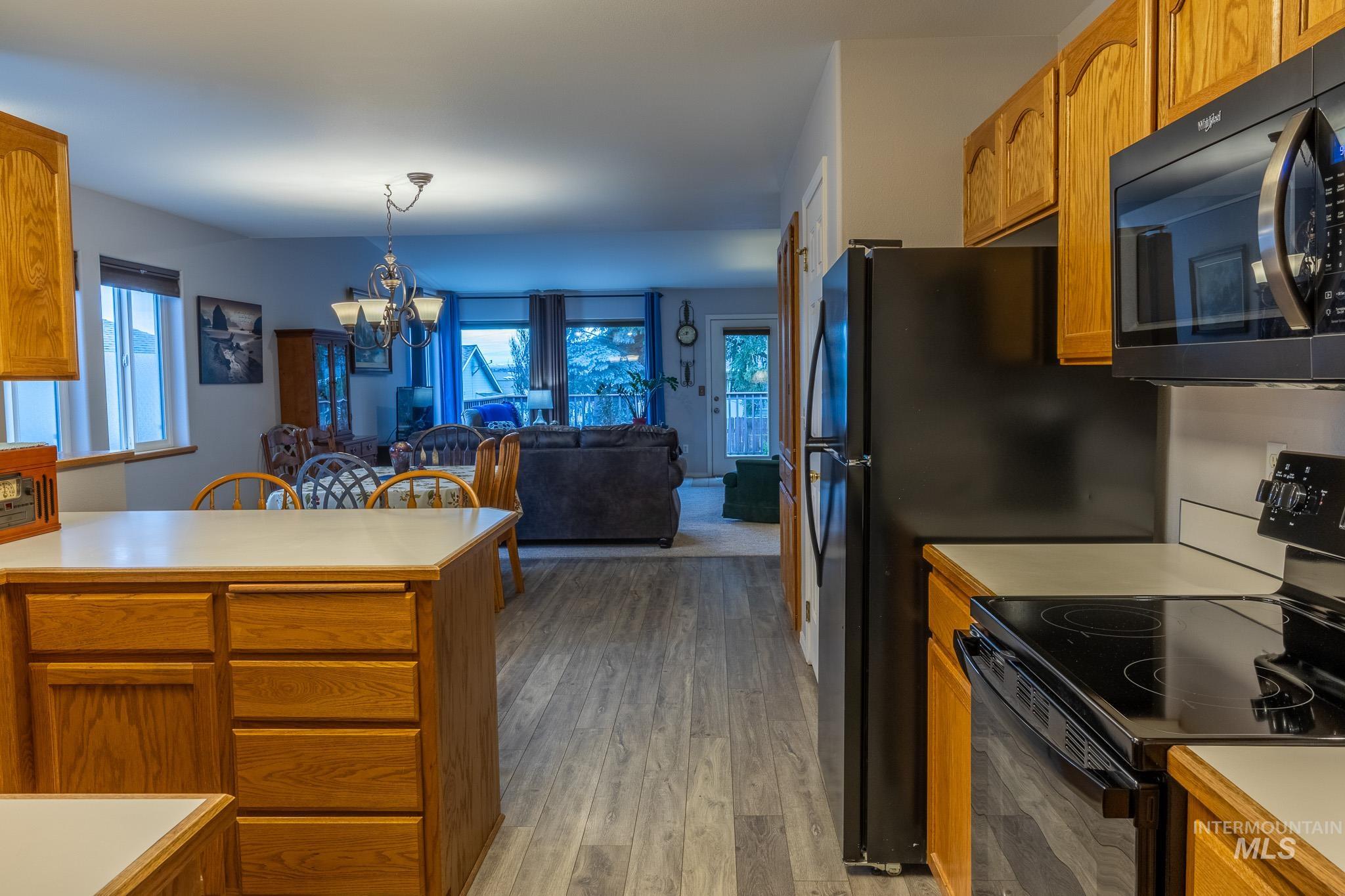 925 Hawthorne Street, Unit A Lewiston, ID 83501 - Photo 8 of 25 Kitchen featuring light countertops, black appliances, brown cabinets, a chandelier, and light wood-style flooring