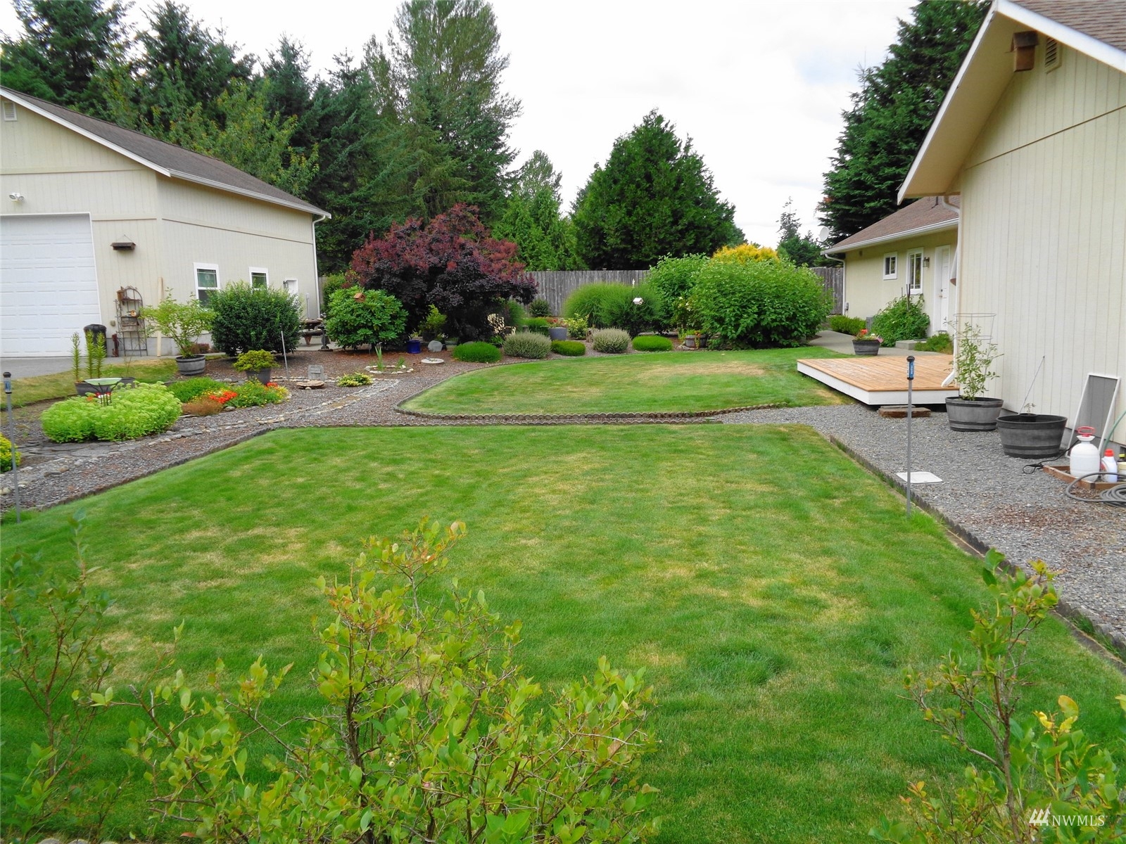 9517 185th Avenue Southwest Rochester, WA 98579 - Photo 5 of 28 a view of a white house in front of a yard with potted plants and large trees