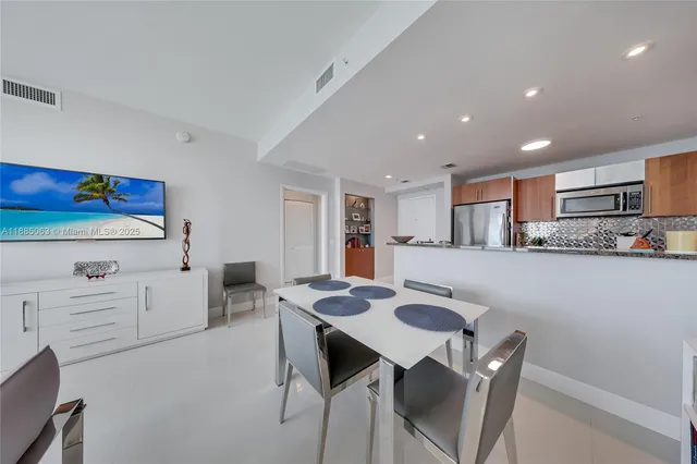 a living room with stainless steel appliances furniture a dining table and kitchen view
