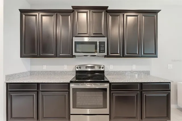 a kitchen with granite countertop cabinets stove and microwave
