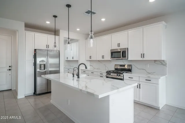 a kitchen with stainless steel appliances a stove a sink a refrigerator a center island a stove and cabinets