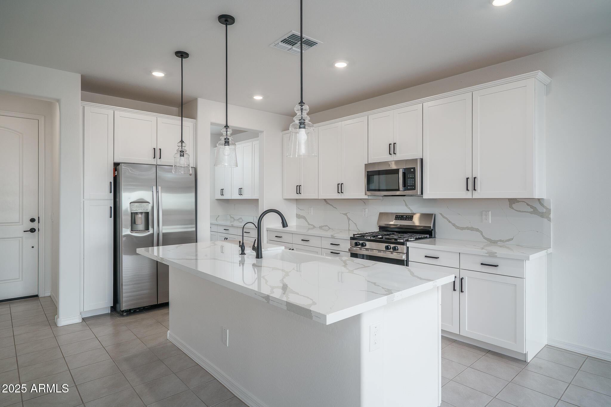 20607 West Rancho Drive Buckeye, AZ 85396 - Photo 5 of 32 a kitchen with stainless steel appliances a stove a sink a refrigerator a center island a stove and cabinets