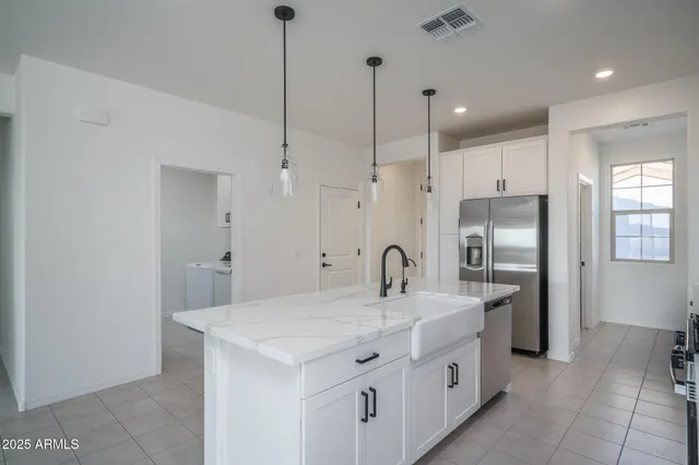 a kitchen with stainless steel appliances a sink a refrigerator a center island a stove and cabinets