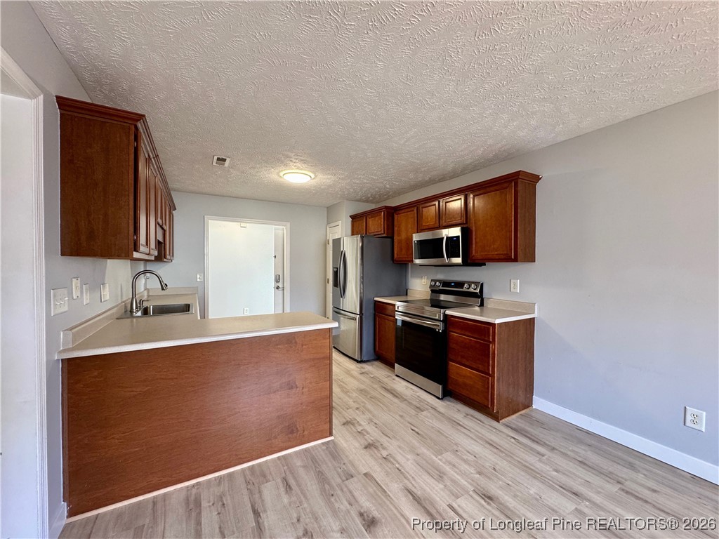 5503 Rising Ridge Drive Hope Mills, NC 28348 - Photo 6 of 18 a large kitchen with stainless steel appliances a large counter top a stove a microwave and a sink
