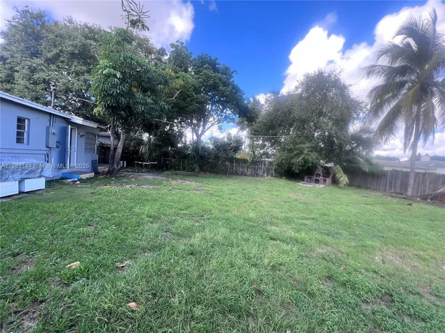 a view of a backyard with potted plants and large trees