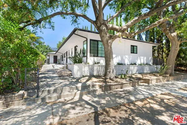 a front view of a house with a tree