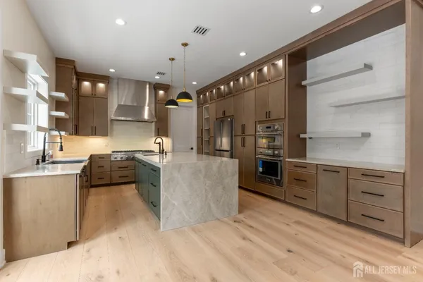 a kitchen with stainless steel appliances kitchen island granite countertop a refrigerator and a stove top oven