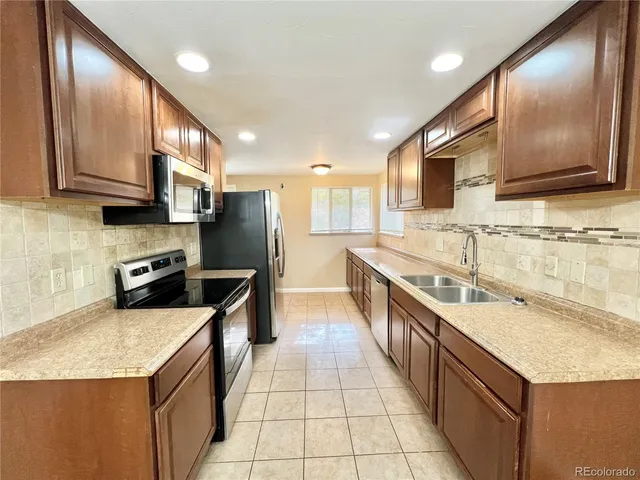 a kitchen with stainless steel appliances granite countertop a sink a stove top oven a refrigerator a sink and dishwasher