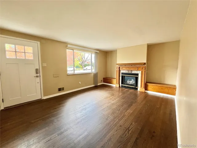 an empty room with wooden floor a fireplace and windows