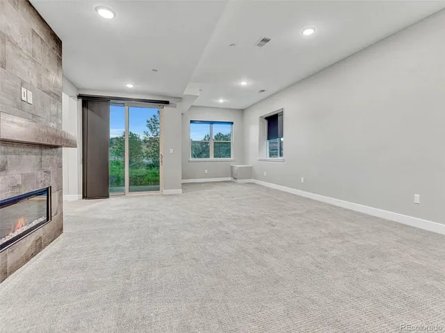 an empty room with windows and fireplace