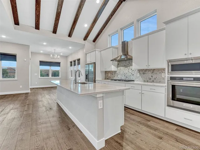 a kitchen with stainless steel appliances granite countertop a kitchen island hardwood floor sink and stove