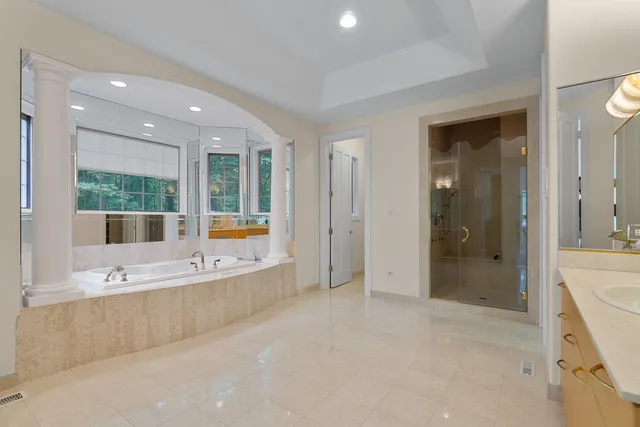 a bathroom with a tub a sink a mirror and a shower