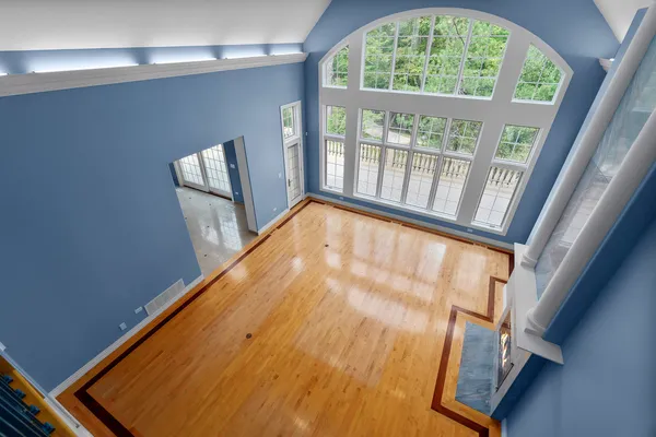 a view of an empty room with a window and wooden floor