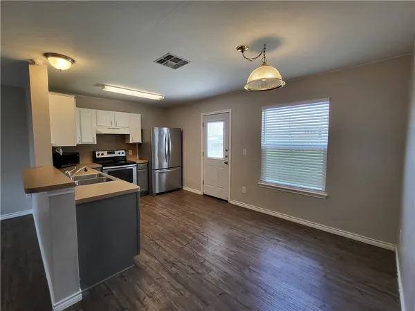 a kitchen with stainless steel appliances granite countertop a refrigerator stove top oven and cabinets