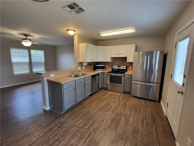 a kitchen with stainless steel appliances granite countertop a stove a sink dishwasher a refrigerator and a stove with wooden floor