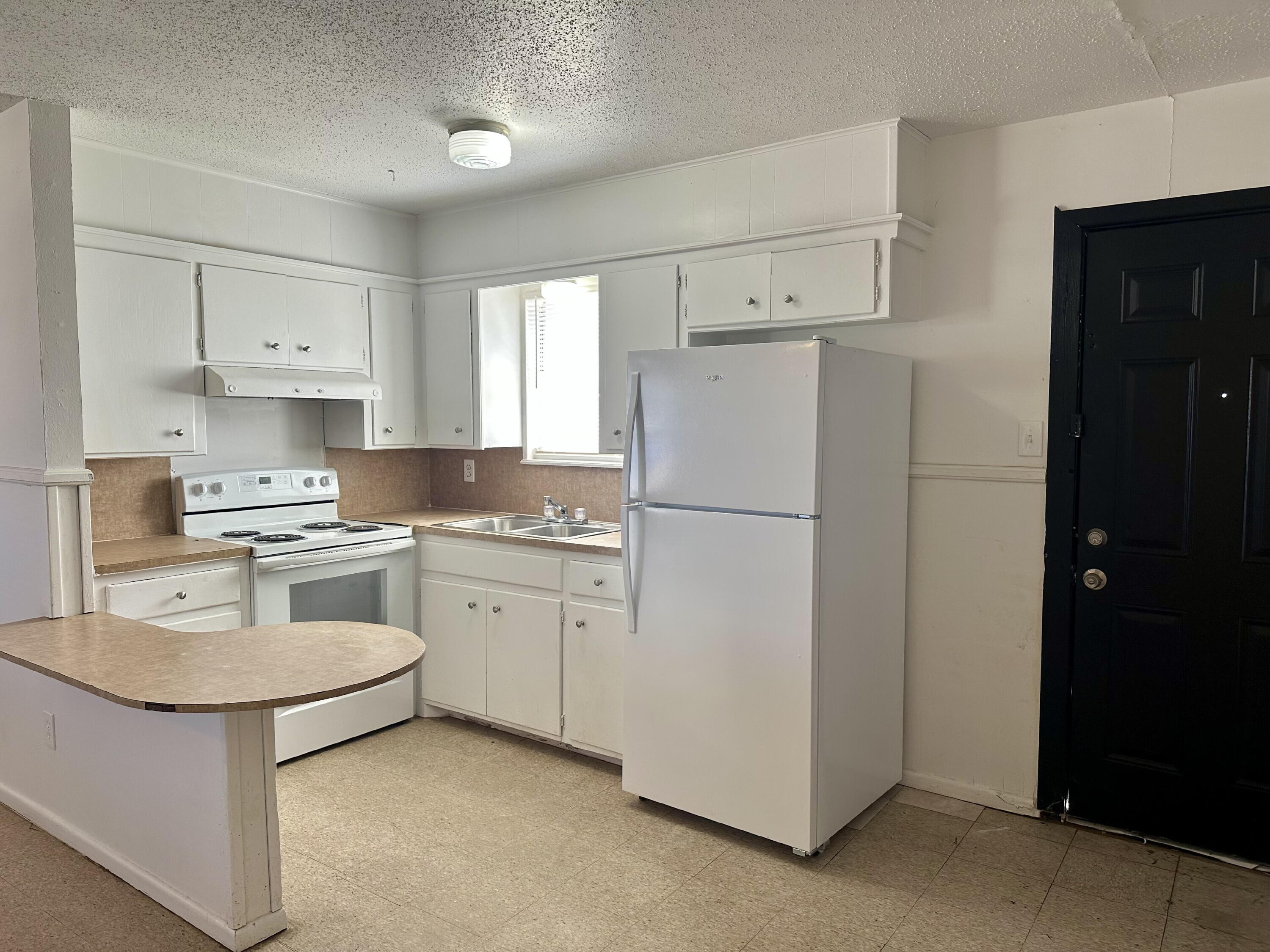 1119 46th Street, Unit B Lubbock, TX 79412 - Photo 4 of 9 a kitchen with white cabinets and white appliances