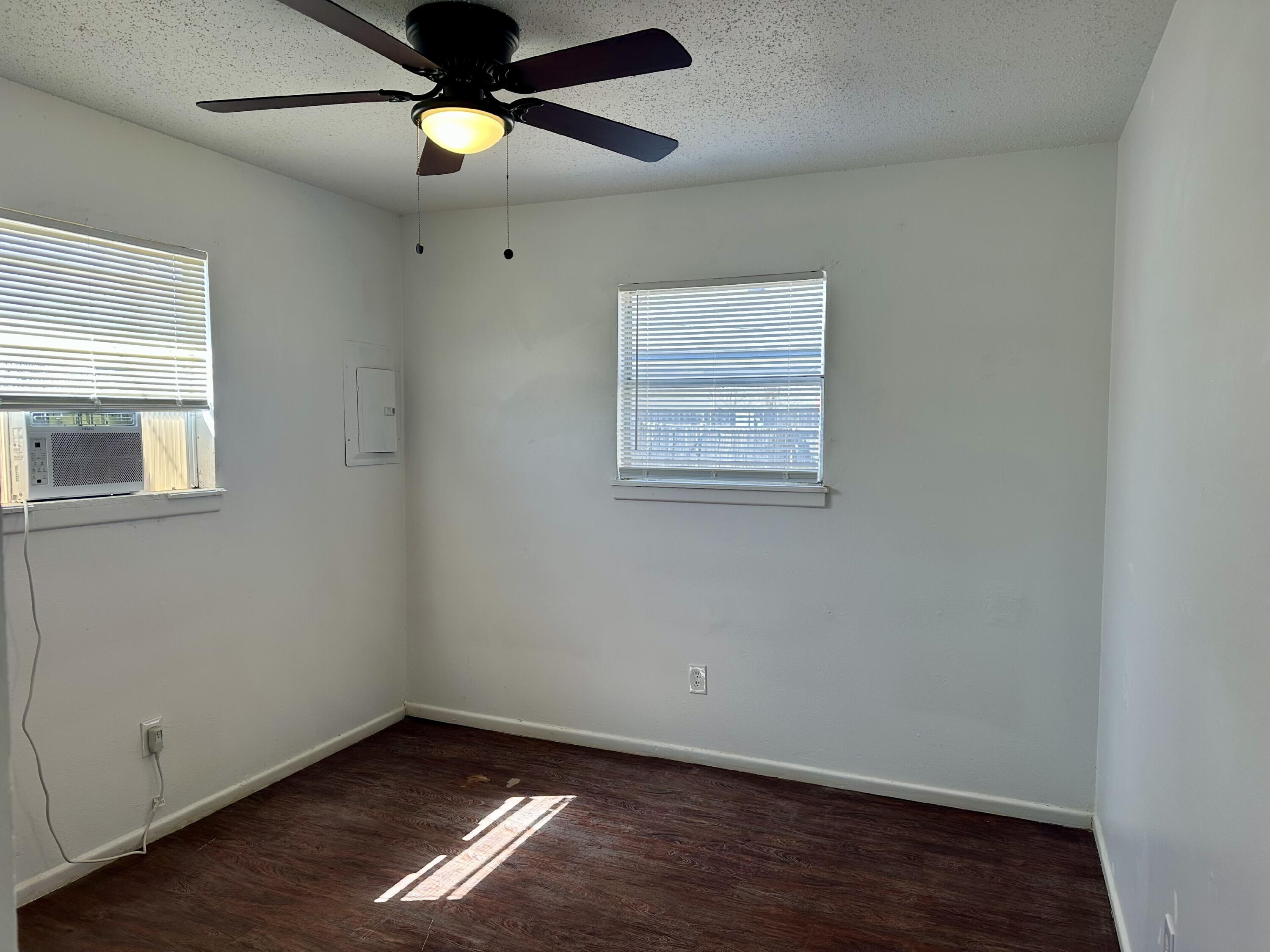 1119 46th Street, Unit B Lubbock, TX 79412 - Photo 7 of 9 an empty room with wooden floor chandelier fan and windows