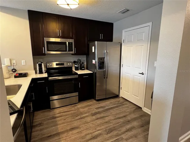 a kitchen with a refrigerator stove and wooden cabinets