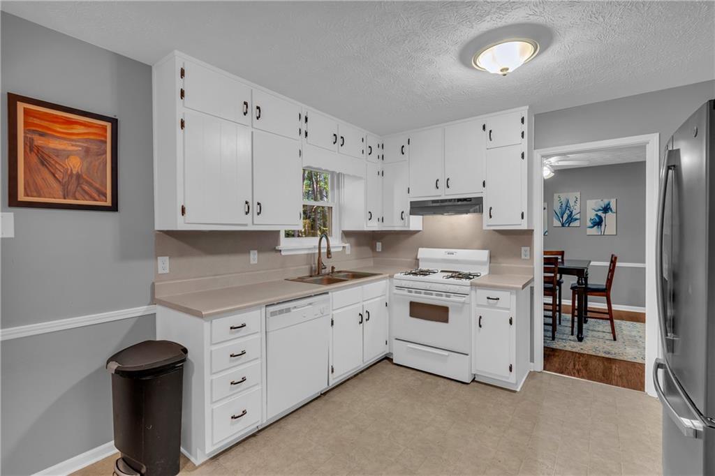 4907 Habersham Ridge Southwest Lilburn, GA 30047 - Photo 18 of 76 a kitchen with granite countertop white cabinets and white appliances