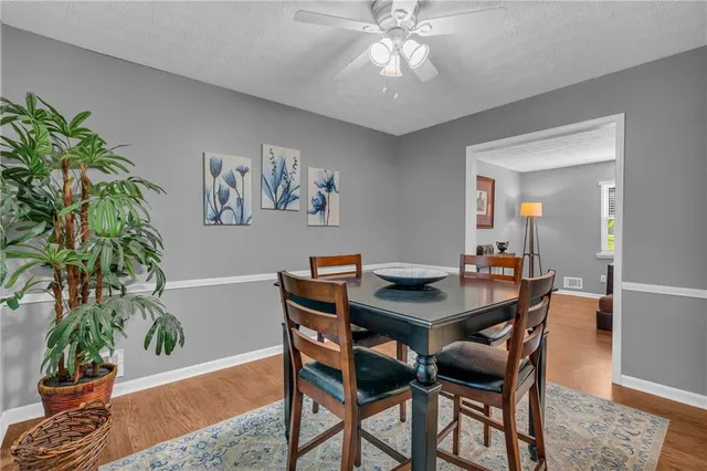 a kitchen with stainless steel appliances a refrigerator a stove a sink dishwasher a dining table and chairs with wooden floor