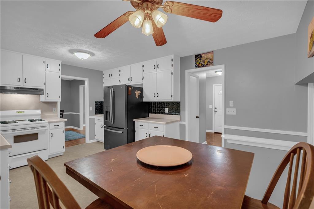 4907 Habersham Ridge Southwest Lilburn, GA 30047 - Photo 30 of 76 a kitchen with stainless steel appliances a refrigerator a stove a sink dishwasher a dining table and chairs with wooden floor