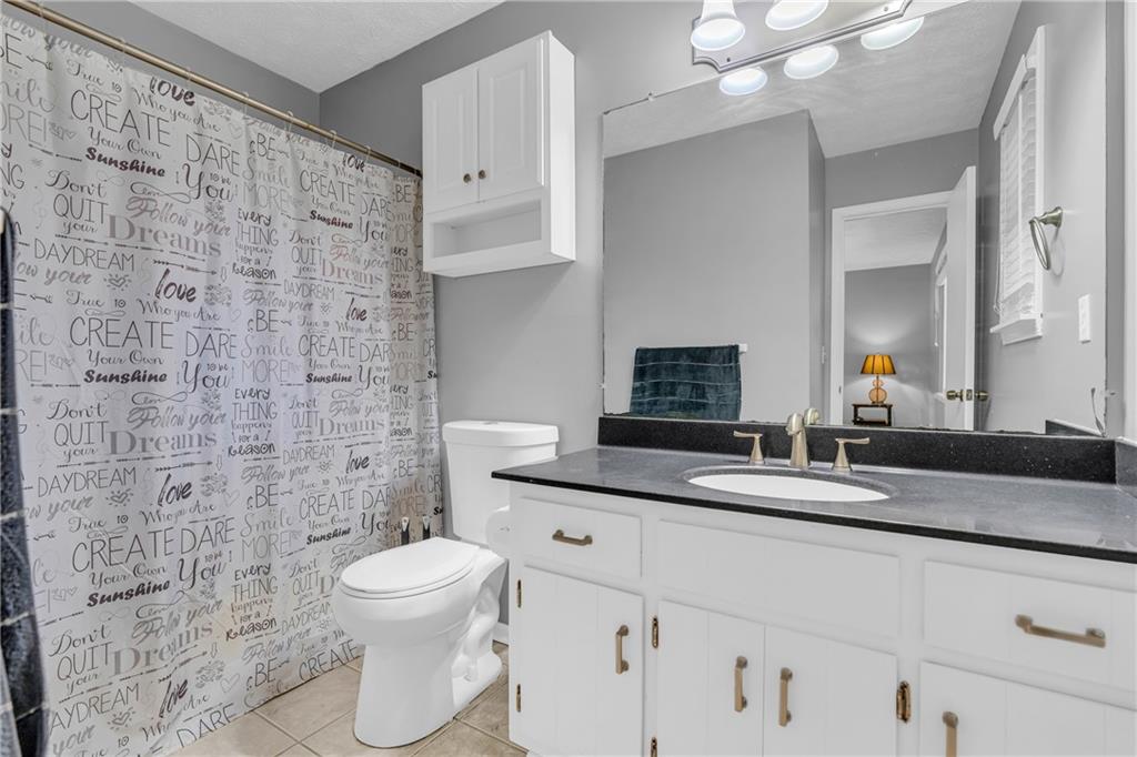 4907 Habersham Ridge Southwest Lilburn, GA 30047 - Photo 40 of 76 a bathroom with a granite countertop toilet a sink and a mirror
