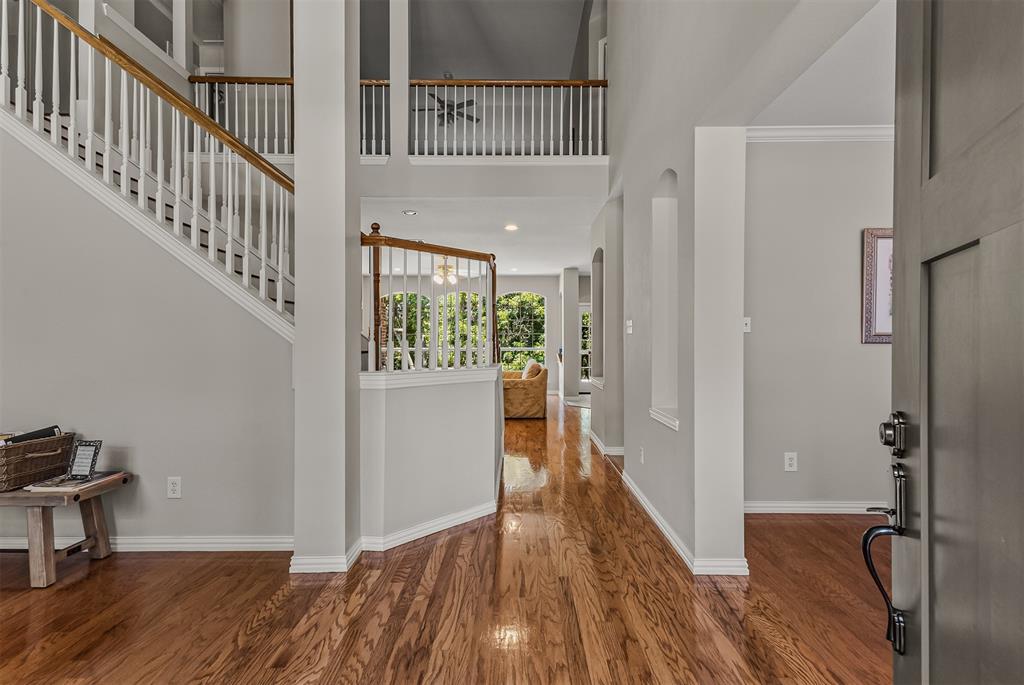 9301 Nottingham Court Rowlett, TX 75088 - Photo 3 of 39 Two-story foyer featuring wood-finish flooring, a grand staircase with white risers and wood handrails, and a second-story balcony
