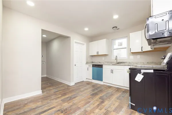 a kitchen with granite countertop a sink cabinets and wooden floor