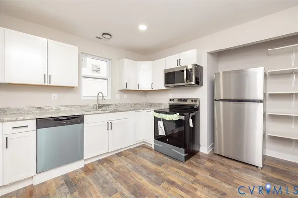 a kitchen with granite countertop a refrigerator and a stove top oven