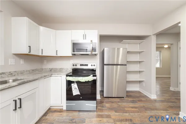 a kitchen with stainless steel appliances granite countertop a refrigerator sink and white cabinets