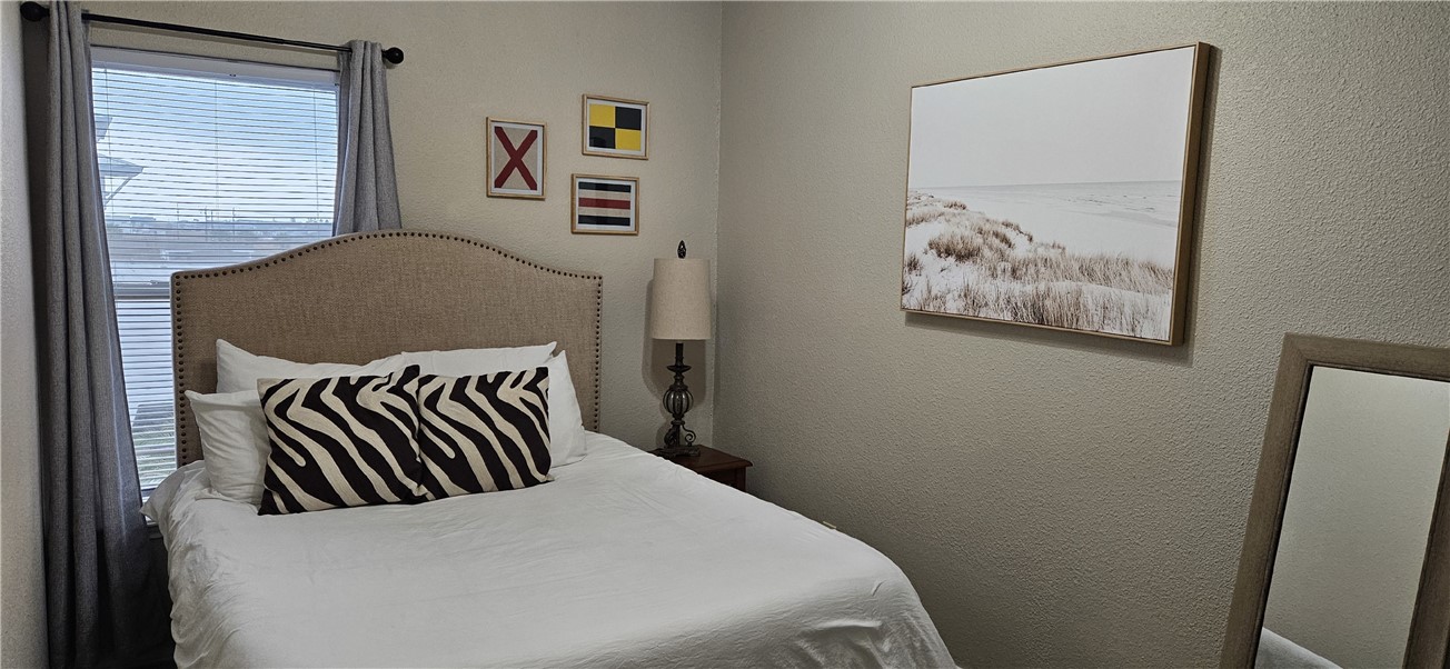 14334 Cruiser Street, Unit 202A Corpus Christi, TX 78418 - Photo 31 of 38 a bedroom with a bed and a painting on the wall