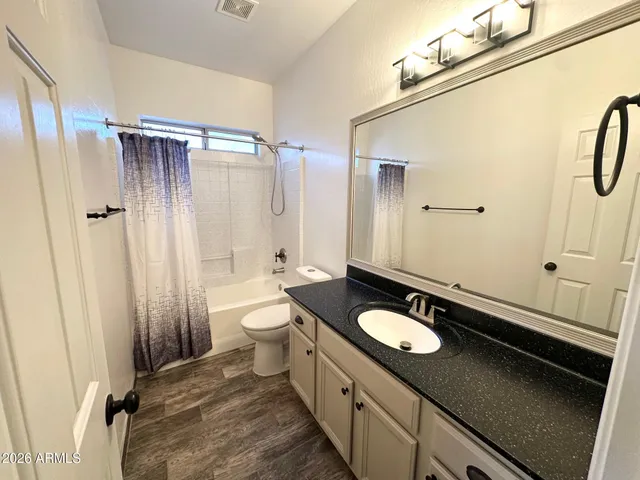 a bathroom with a granite countertop sink toilet a mirror and shower