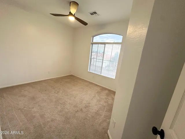 an empty room with windows and fan