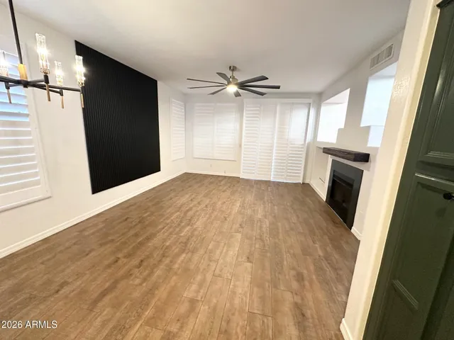 an empty room with wooden floor cabinet and windows