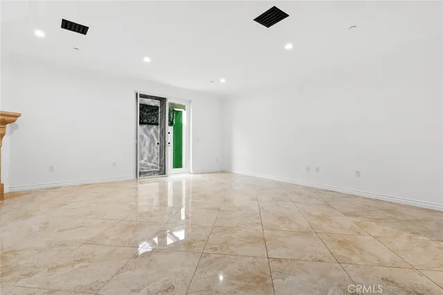 an empty room with an entryway and kitchen view