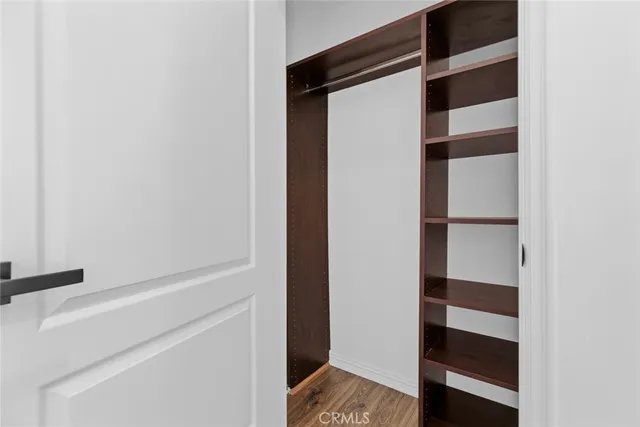 an empty room with wooden floor closet and windows