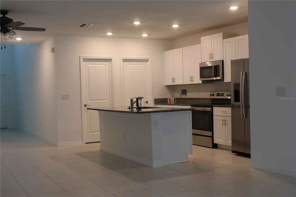 6259 Back Forty Loop Zephyrhills, FL 33541 - Photo 6 of 22 a kitchen with kitchen island white cabinets and stainless steel appliances