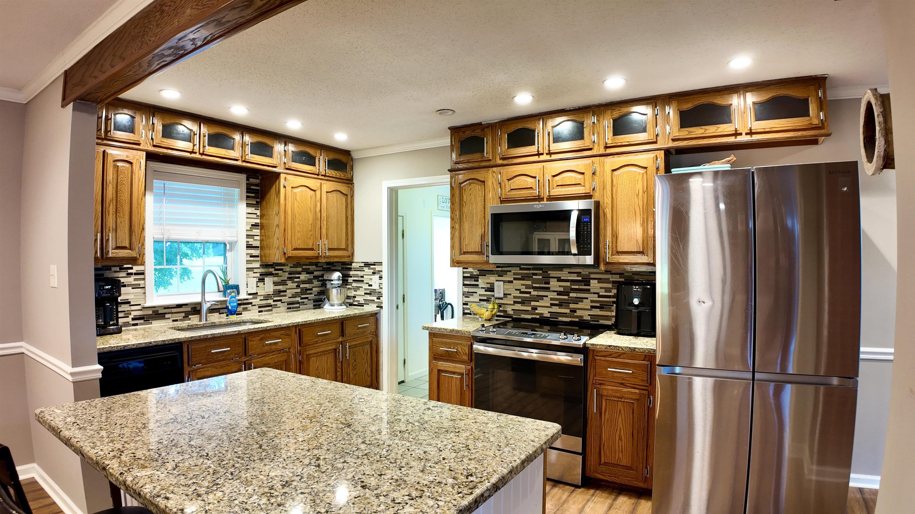 3312 Old Memphis Road Covington, TN 38019 - Photo 14 of 32 Kitchen featuring stainless steel appliances, sink, light stone countertops, light hardwood / wood-style floors, and backsplash